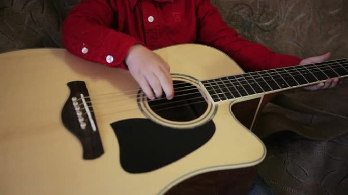 穿着红色衬衫的小男孩弹吉他