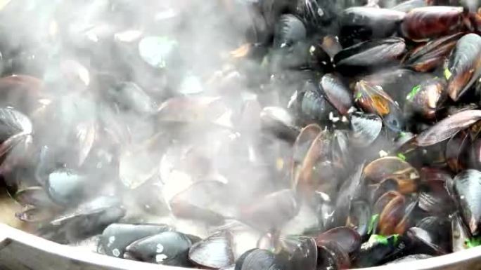 贝壳中的贻贝在火上的锅中煮熟，食物在街上准备，海鲜外卖