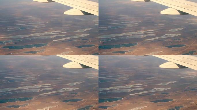 飞机的翅膀在地球上飞来飞去，上面有湖泊。飞机窗口的视图