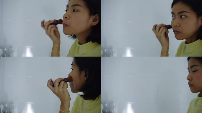 亚洲妇女在脸颊上涂刷胭脂粉