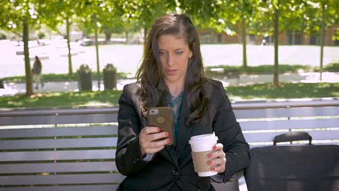 在公园长椅上看手机应用技术的美女