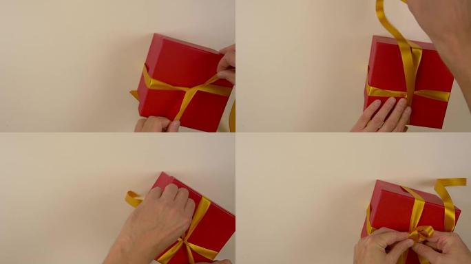 快速运动时间流逝。包装红色礼品盒。高加索人手包装礼品盒。男人的手在红色纸板箱上系上丝带。俯视图特写。
