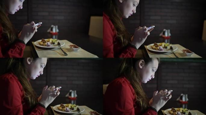 穿着红色连衣裙的女孩坐在餐厅的桌子旁，用电话。