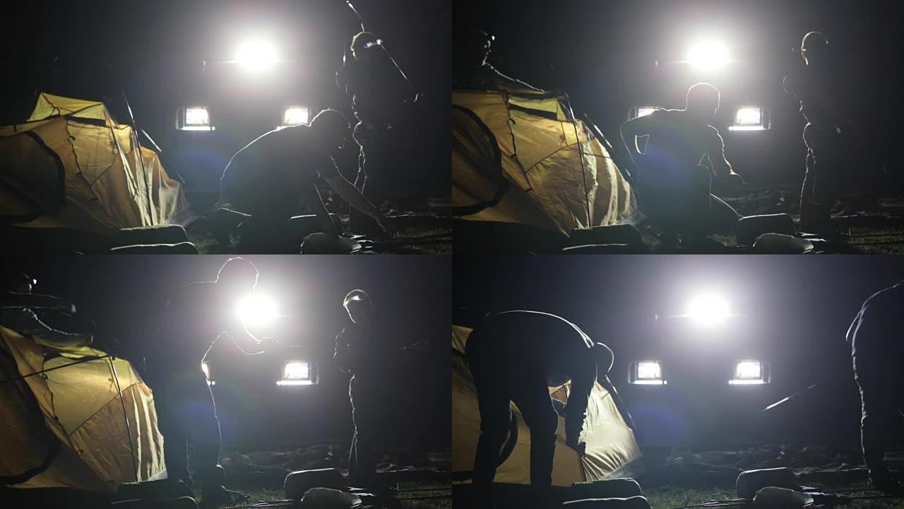 两名成年男子和儿童从SUV在ligh搭建帐篷的夜间拍摄。