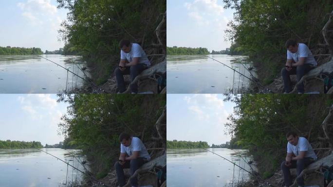 渔夫坐在既定的spinnings附近的河岸上时使用智能手机