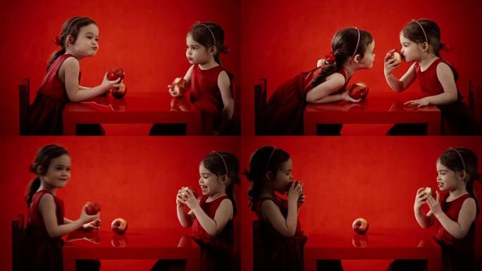 两个小女孩在红色桌子上吃苹果