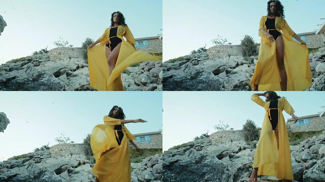 女人站在岩石上挥舞着黄色的长裙