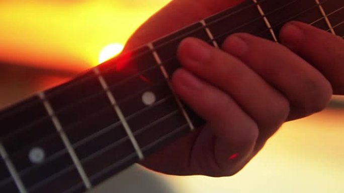 男子特写电吉他在日落和夏日傍晚的湖边演奏摇滚