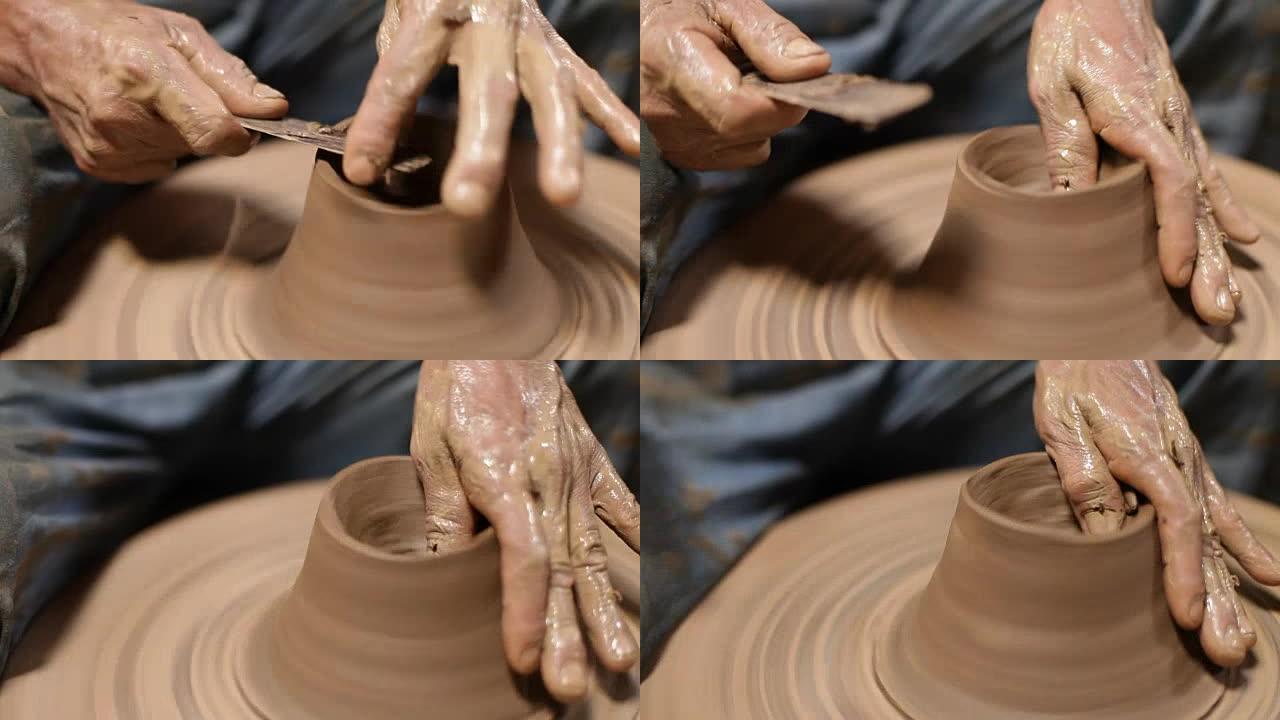 在陶轮上工作的手的特写，塑造了一个陶罐。泰国