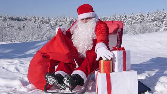 圣诞老人把圣诞礼物放在雪地上的礼品袋里