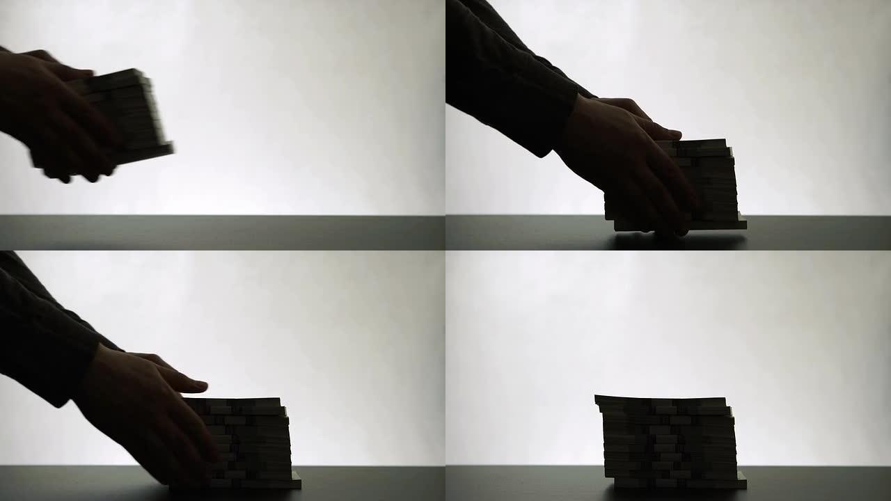 一个人的手放在桌上一叠纸币上