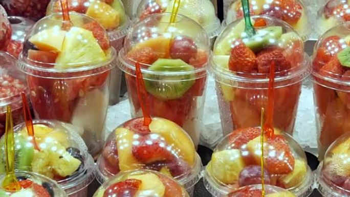 新鲜的新鲜包装在塑料玻璃混合物中，混合了西瓜，猕猴桃，梨，苹果，芒果，石榴，草莓的水果，叉子紧贴在其
