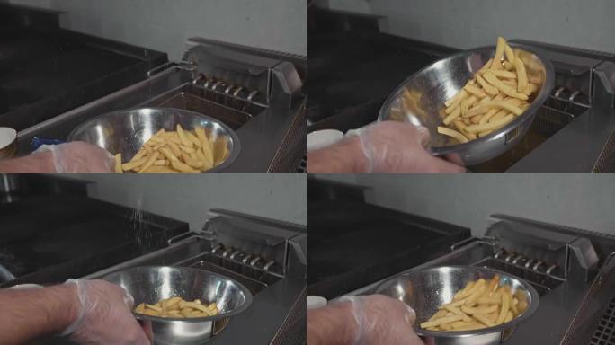 厨师在钢碗中混合和腌制炸薯条，特写慢动作。