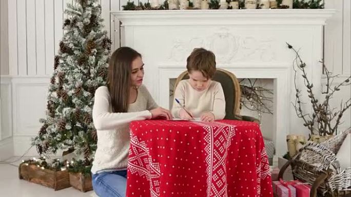 年轻的母亲帮助她的小儿子给圣诞老人写了一封信