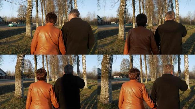 日落时分，爱在公园散步的老年夫妇。附近有一条路。一个穿着棕色皮夹克的女人。这个男人穿着一件黑色毛衣