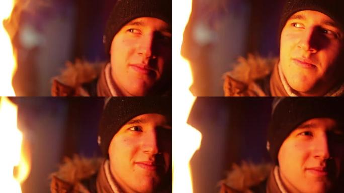 穿着冬装的年轻人在火光下看着相机