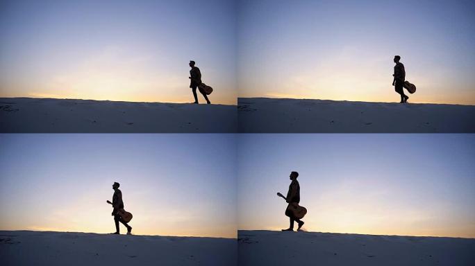 一个庄严的阿拉伯人手拿吉他走在沙漠的小山丘上，在夏天的傍晚，夕阳西下