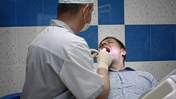 男性牙医检查其男性客户的牙齿