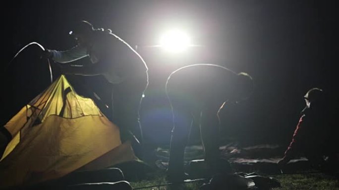 两名成年男子和儿童从SUV在ligh搭建帐篷的夜间拍摄。