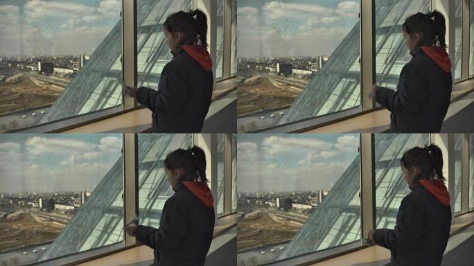 小女孩看着摩天大楼的窗户