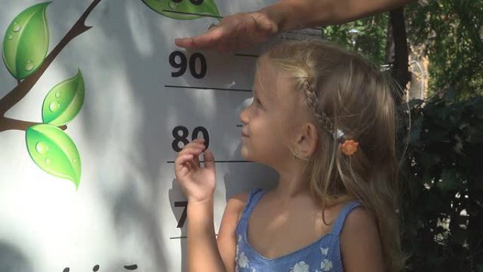 孩子玩耍，检查她的高个子，母亲测量小女孩的身高