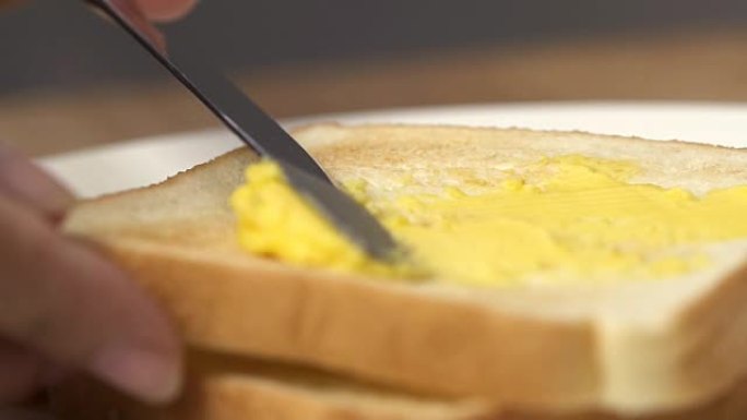 把黄油涂在一块面包上。
