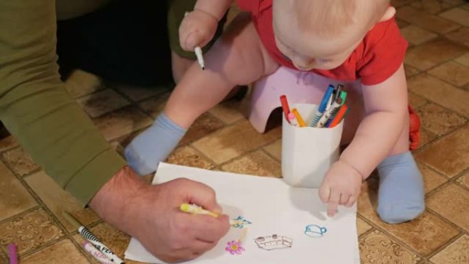迷人的婴儿坐在锅上，用祖父的记号笔在纸上画画。男孩在家里撒尿和玩耍。孩子1年
