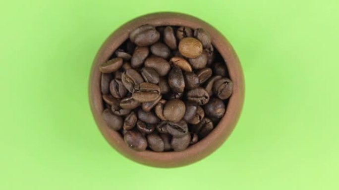 咖啡豆在绿色屏幕上隔离的锅中旋转。