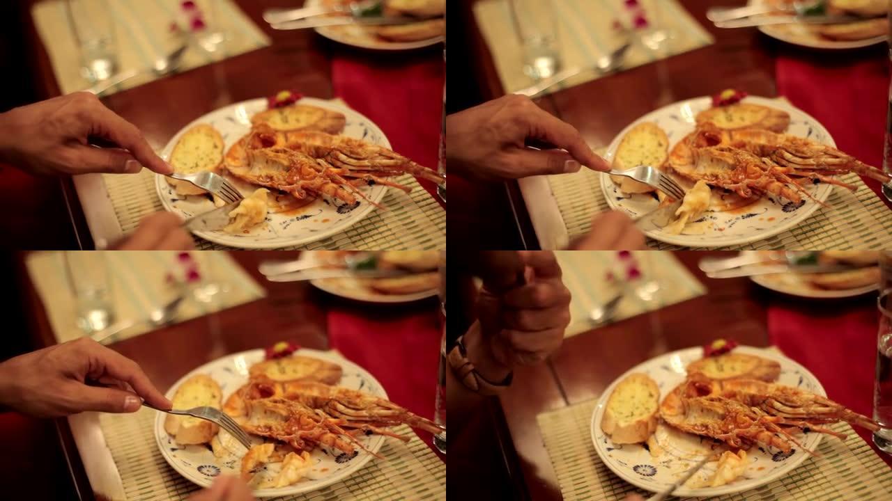 用叉子和刀子在盘子上吃龙虾的人的特写手