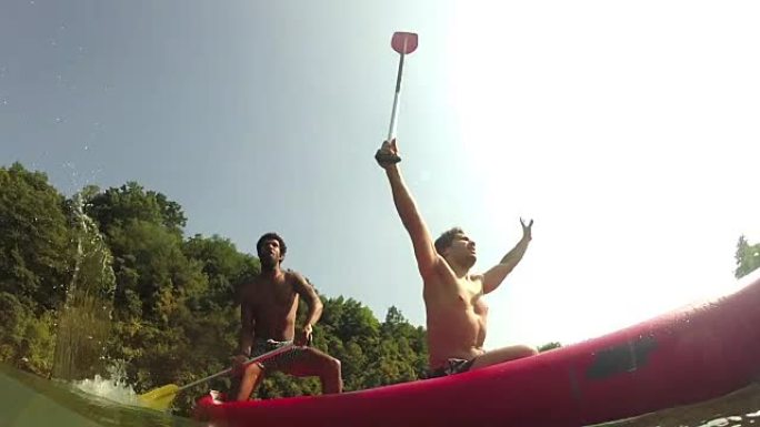 两个男性朋友在独木舟上挥舞着桨