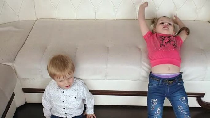 两个小孩滑下沙发玩耍。