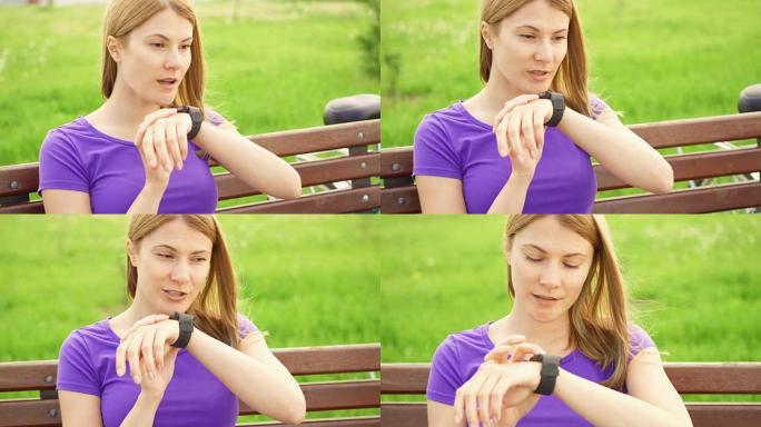 在公园里用智能手表发短信的女人。使用她的智能手表，通过口语应用程序向朋友发送消息