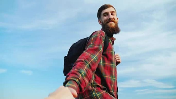 伸出援助之手。一个年轻人帮助伴侣爬山。他拉着她的手。概念-帮助、支持、可靠的合作伙伴、团队合作