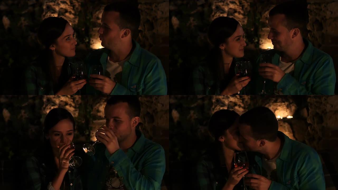 恋爱中的年轻夫妇喝着酒，在烛光下接吻