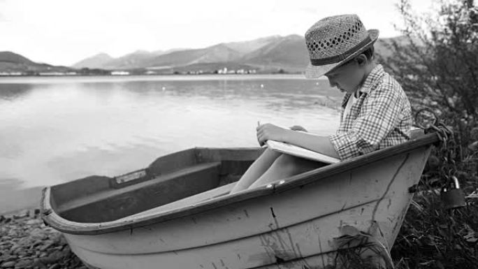 一个男孩坐在渔船上看书的黑白视频