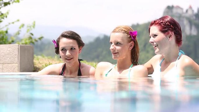 三个女孩坐在游泳池里聊天