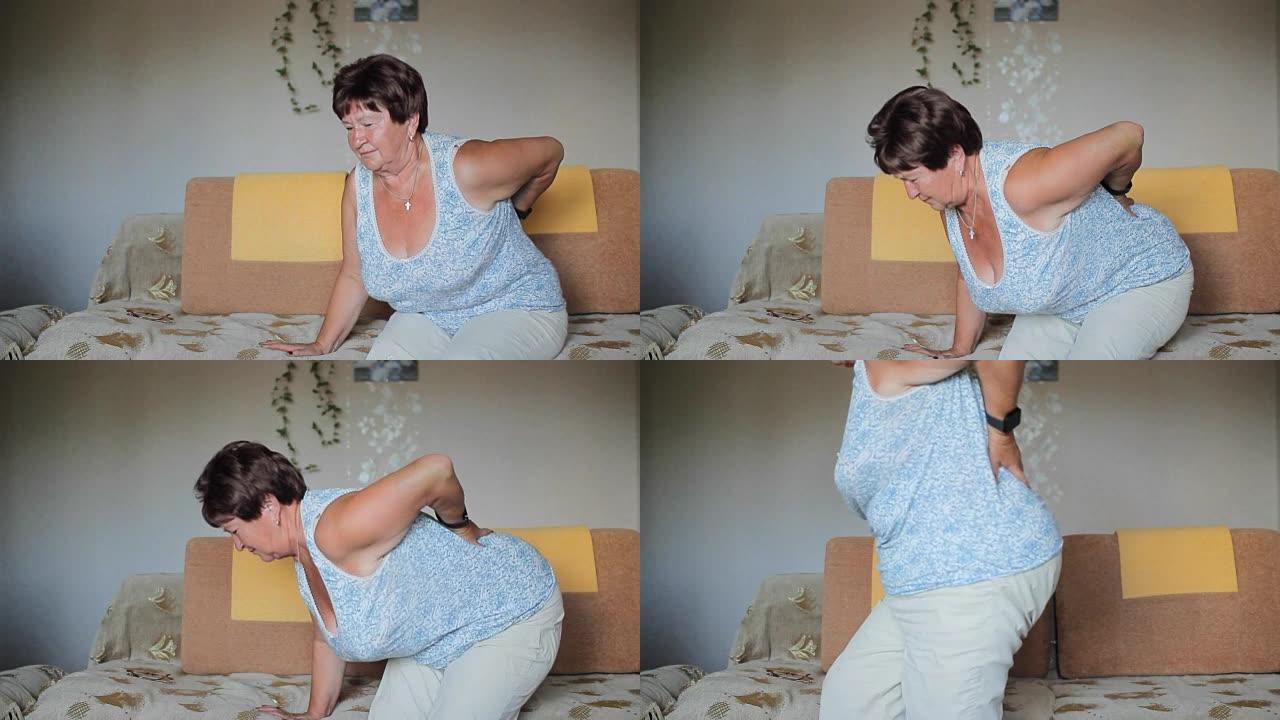 成年女性背痛。一个女人试图从沙发上站起来，但她的背部剧烈疼痛