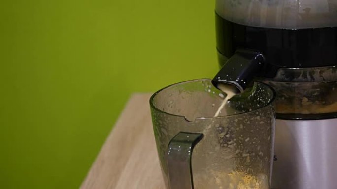 榨汁机的汁液倒入杯子中。特写