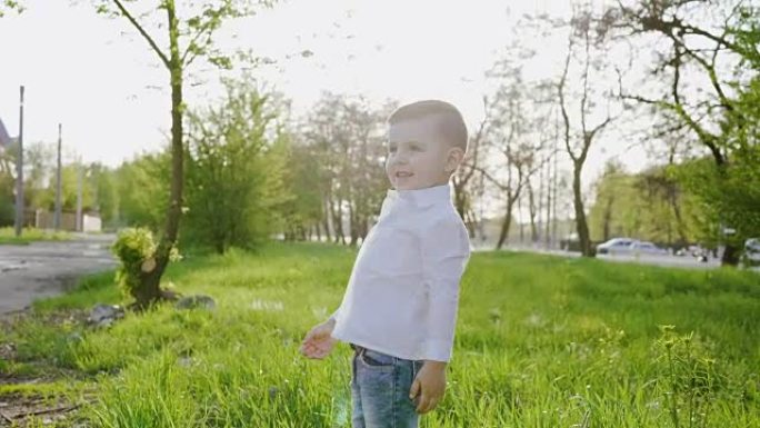 小绅士走在公园的草坪上，对着镜头微笑