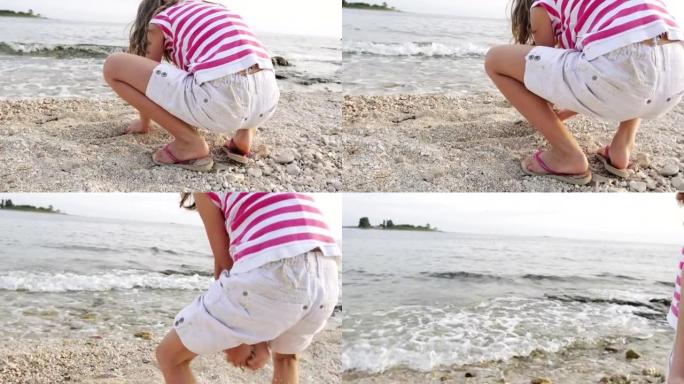 慢动作: 小女孩在海滩上玩鹅卵石