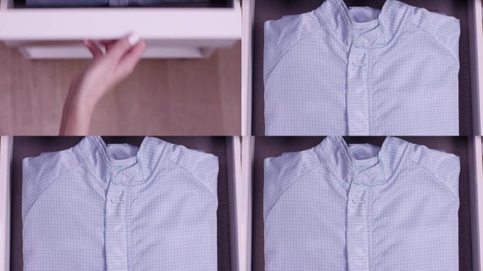 女性手打开白色衣柜或蓝色衬衫储物柜。橱柜、储物柜、橱柜、壁橱或盒子里蓝色条纹的蓝色昂贵衬衫