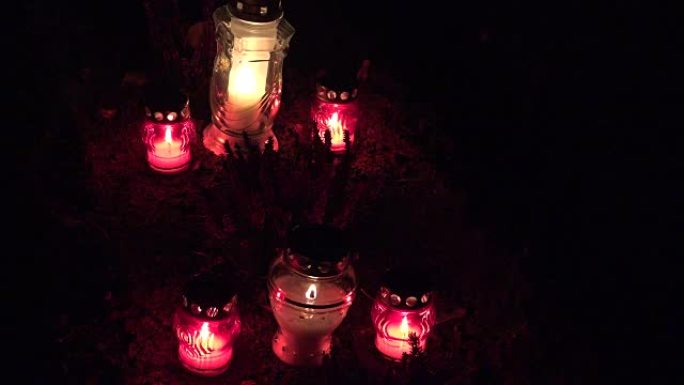 晚上墓地里的坟墓上燃烧的蜡烛。万圣节前夜。FullHD