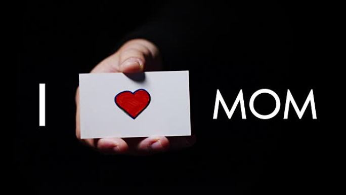 一只手展示了一张浪漫的卡片，上面写着 “我爱妈妈”。概念: 爱，帮助他人，喜欢，爱家庭，爱母亲，感谢