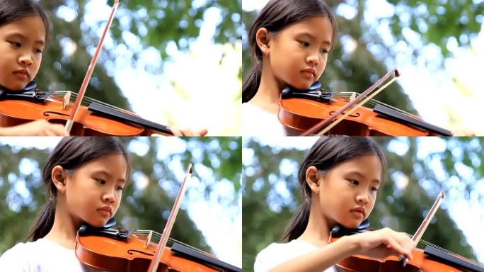 亚洲小女孩在公园拉小提琴