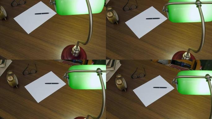 作家的桌子上有书籍，时钟，眼镜，干净的纸和绿色的灯打开