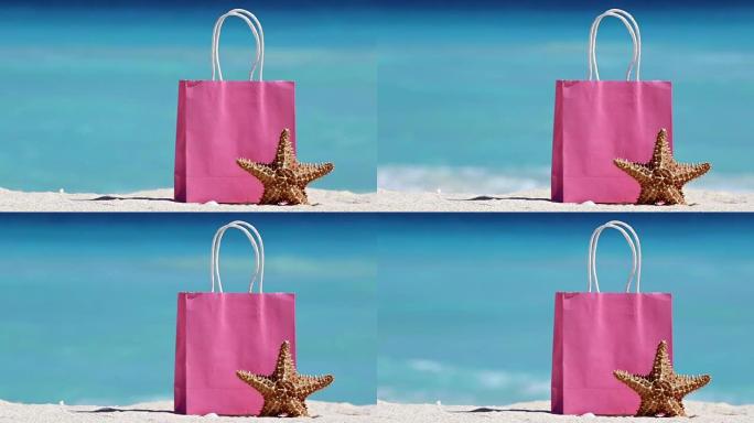 粉色购物袋和海星在沙滩上抵御绿松石加勒比海海水