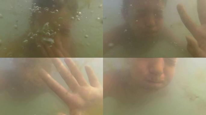 男孩在海里的泥水里游泳，海藻，阳光，汹涌的大海