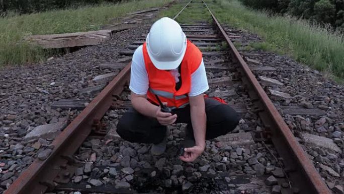 对讲机上的铁路工人检查铁轨漏油