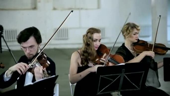 三位小提琴家和指挥家演奏音乐