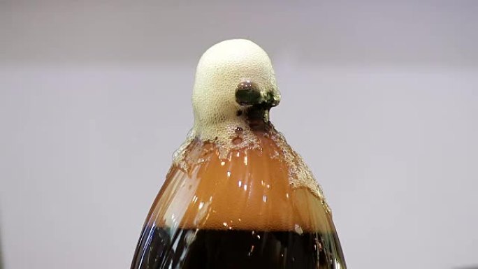 Man fail打开一个装有苏打水的塑料瓶的盖子。克瓦斯，黑啤酒泡沫